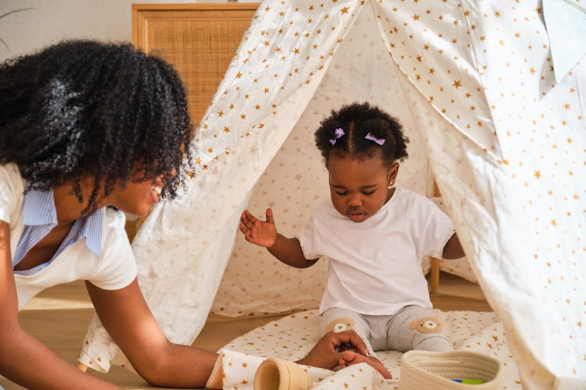 A woman playing with a child in a tent