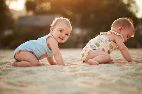 Twin baby girls during sunset on a tropical beach vacation.