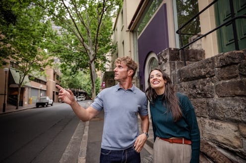 Two young adults are happily exploring the streets of Sydney. They smile as they take in the sights,...