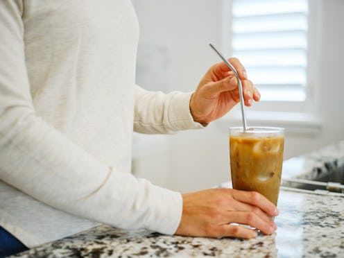 A woman putting a reusable drinking straw into a cold beverage.