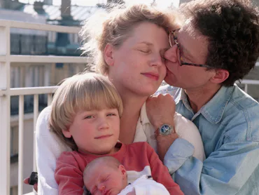 Owen Franken kisses his wife, Annemiek, as she sits with their son, Tunui, and their newborn daughte...