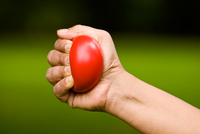 Hand squeezing a stress ball isolated on natural bokeh background