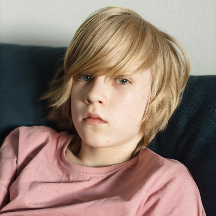 Teenage boy with long blond hair staring blankly at the camera.