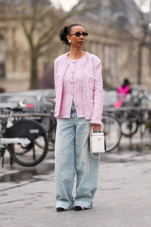 A guest wears black sunglasses, pearl Chanel earrings, black bow hair accessory, white light pink pa...