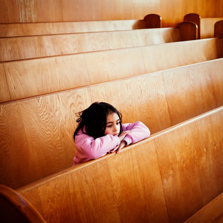 Girl looks forlorn as she sits alone on a bench in a courtroom.