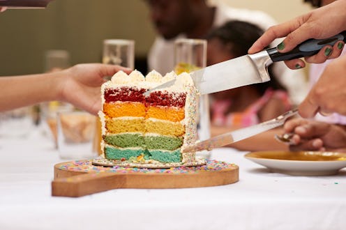 Hands of guests with knife taking cake slice at dining table during birthday celebration in back yar...