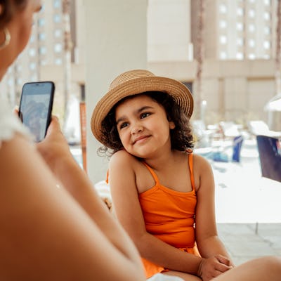 Mother taking a photo of her daughter in the pool.
