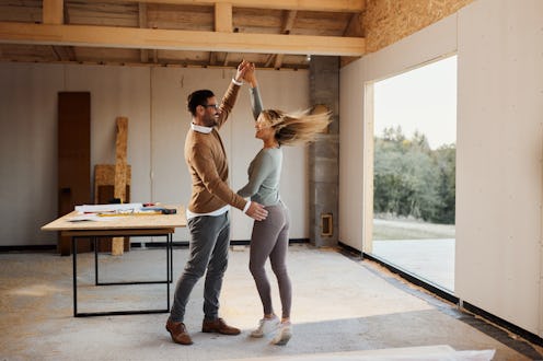 Cheerful woman having fun while dancing with her boyfriend on a construction site in their house.