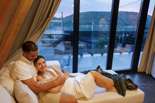 Young couple in love lying on sofa and hugging while spending romantic weekend in glamping house