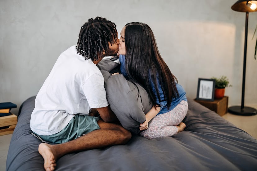 Man kisses his wife while relaxing in bed at home