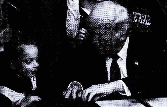 US President Donald Trump speaks with a little girl as he selects a pen to sign the No Men in Women'...