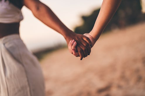 Two people holding hands outdoors, expressing connection, intimacy, and trust. The image showcases a...