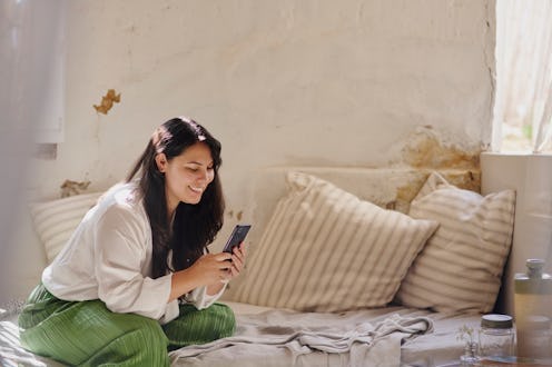 Smile, woman and relax with phone on sofa for communication, social media and reading ebook. Happy, ...