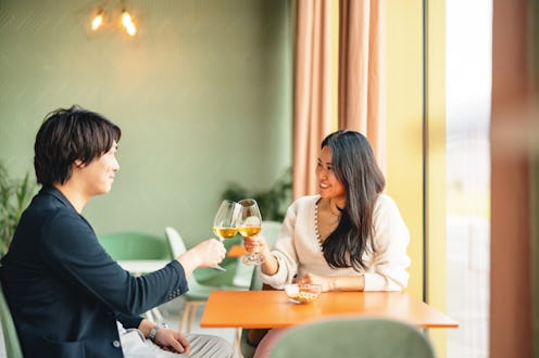 A Japanese couple shares a romantic moment in a cozy coffee shop, clinking glasses and enjoying each...