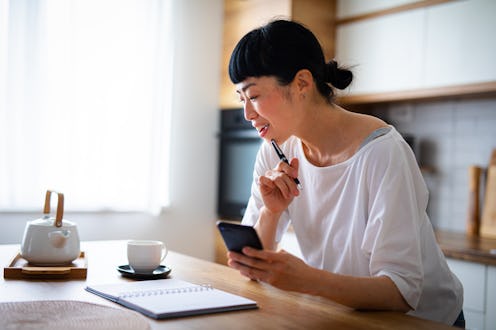 Woman drinking a cup of coffee  in the kitchen while planning her day
