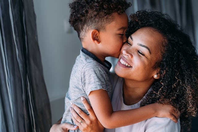 A joyful mother and her young son share a loving moment, with the boy giving her a kiss on the cheek...