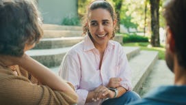 Diverse group of people participating in outdoor community therapy session focused on mental health ...