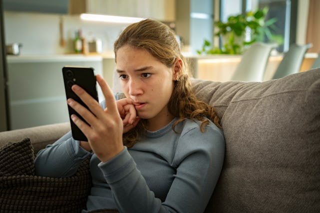 Portrait of a nervous teen girl looking at her smartphone. Teenagers have become more likely to say ...
