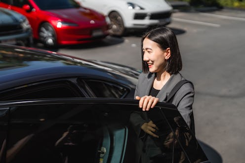 Businesswoman entering EV car shared with her colleagues, ready for the commute to work, embracing t...