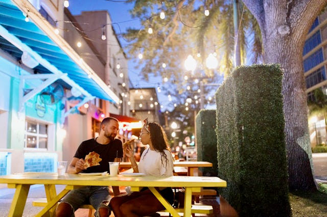 Portrait of a beautiful multiracial couple eating pizza at night