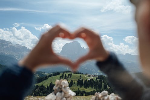 Landscapes of the Italian Dolomites in summer. The mountain Sassolungo fits tin the hand heart shape...