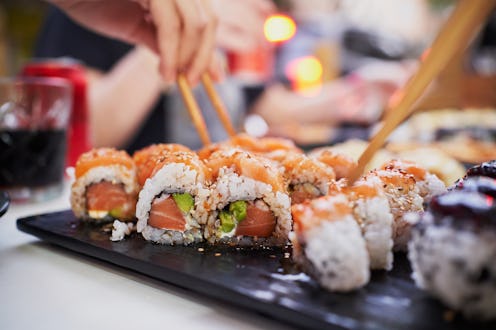 Close-up of uramaki, a type of sushi roll also known as inside-out roll, being taken from a serving ...