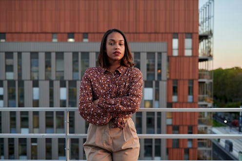 Portrait of woman with crossed arms on rooftop, looking at camera.