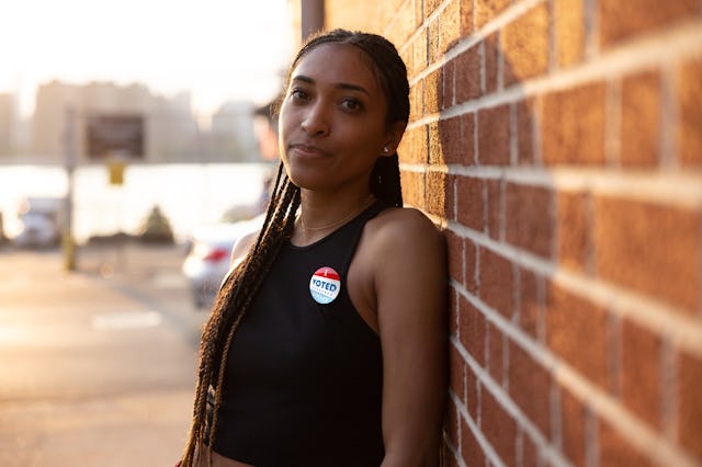 Young woman out of the polling place wearing "I voted" pin. Women politicians encourage voting among...