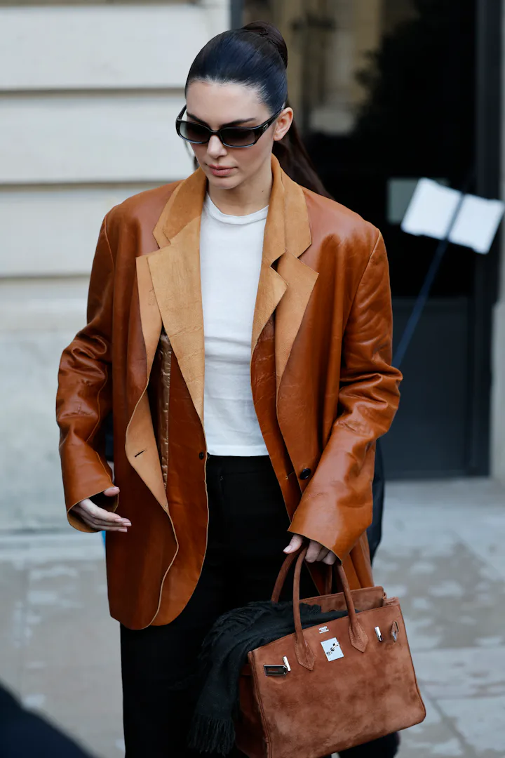 PARIS, FRANCE - JANUARY 27: Kendall Jenner wears white top, brown leather double blazer, brown suede...