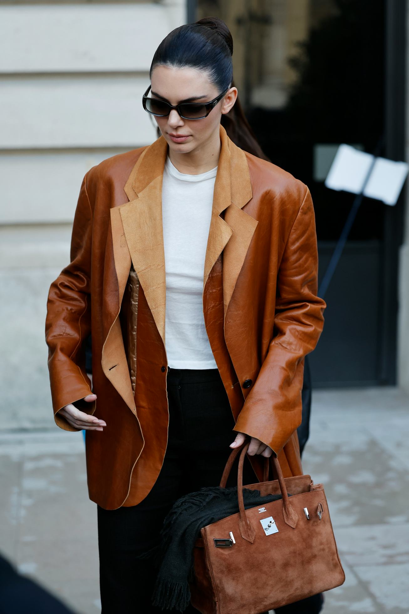 PARIS, FRANCE - JANUARY 27: Kendall Jenner wears white top, brown leather double blazer, brown suede...