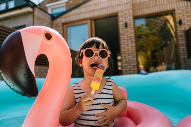 Cute Asian toddler cooling down with ice lolly while enjoying summer in the backyard. Summer vacatio...