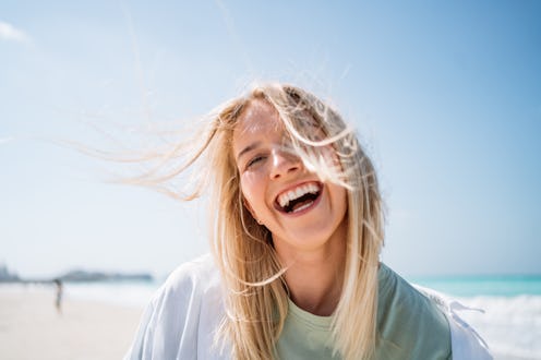 Portrait of happy laughing woman with white teeth against sky and beach