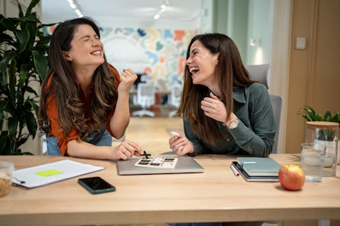 Two cheerful businesswomen taking a break from work and having fun playing tic-tac-toe in the office...
