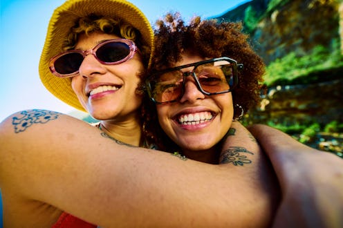 Two happy tattooed young women embracing during their hiking trip