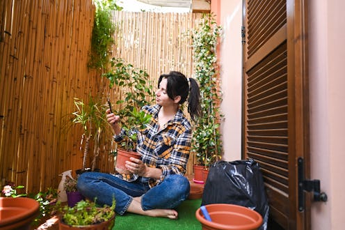 Woman taking pictures of plants on her balcony garden
