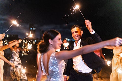 Bride and groom using sparklers with their wedding guests on the beach wedding party