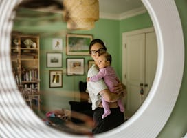 Young mother with baby at home. Young mother dressed in casual clothes wearing glasses, holding 3 mo...