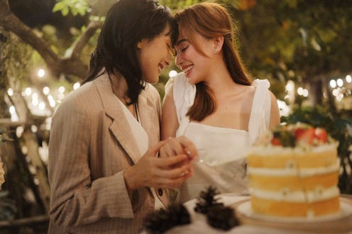 Two lesbian women are sharing a kiss during their wedding ceremony and posing to capture this beauti...