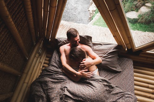 A happy couple lounges together in a bamboo house interior, showcasing love and relaxation.