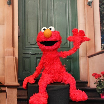 Elmo waves happily from the stoop of 123 Sesame Street.