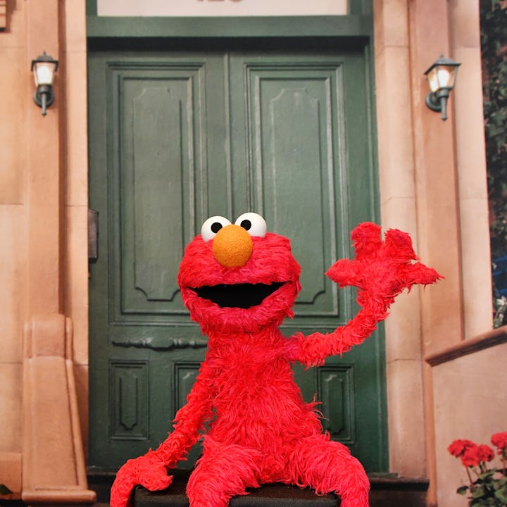 Elmo waves happily from the stoop of 123 Sesame Street.