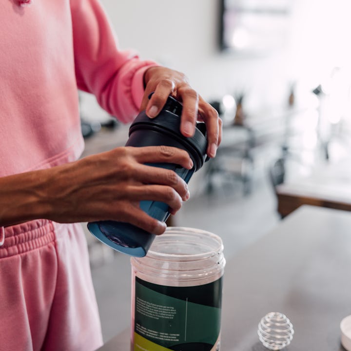 Woman preparing protein shake at home before leaving to the gym.
