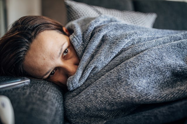 One woman, young woman with Covid-19 symptoms lying on sofa at home.