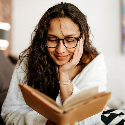 Woman is lying in sofa and enjoying a good book