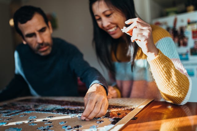 Australian multiethnic couple does a jigsaw puzzle together in their kitchen
