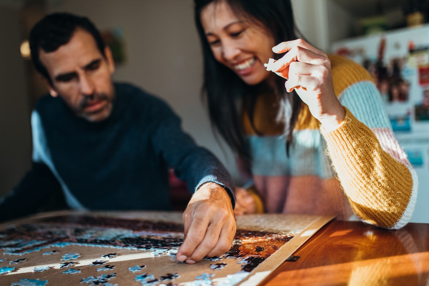 Australian multiethnic couple does a jigsaw puzzle together in their kitchen