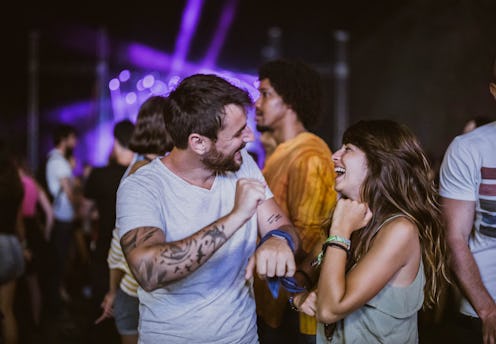 Carefree couple having fun while dancing on music festival by night.
