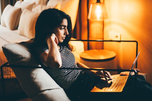 Portrait of woman using laptop at home in the evening.