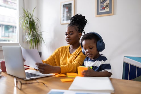 Young mother working from home while taking care of her little son