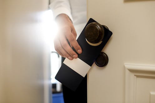 Unrecognizable Caucasian male putting a do not disturb sign on a doorknob in a hotel.